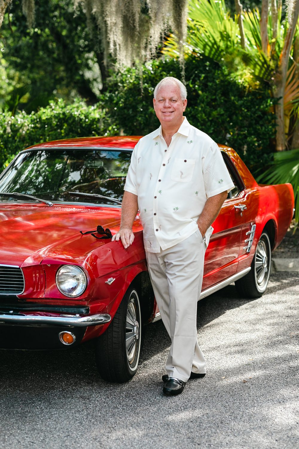 Rob Guthrie leaning on a red classic Mustang